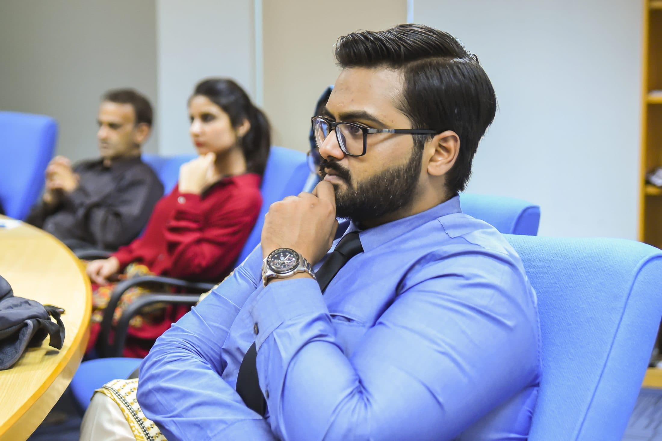 A participant sitting back in a session, hand on chin, thinking something through