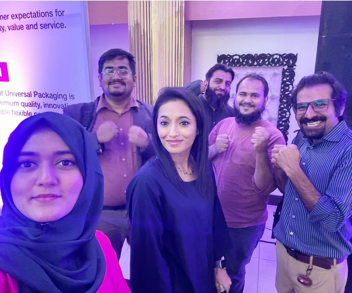 A client team at the end of a session, arms up, in front of their own branding