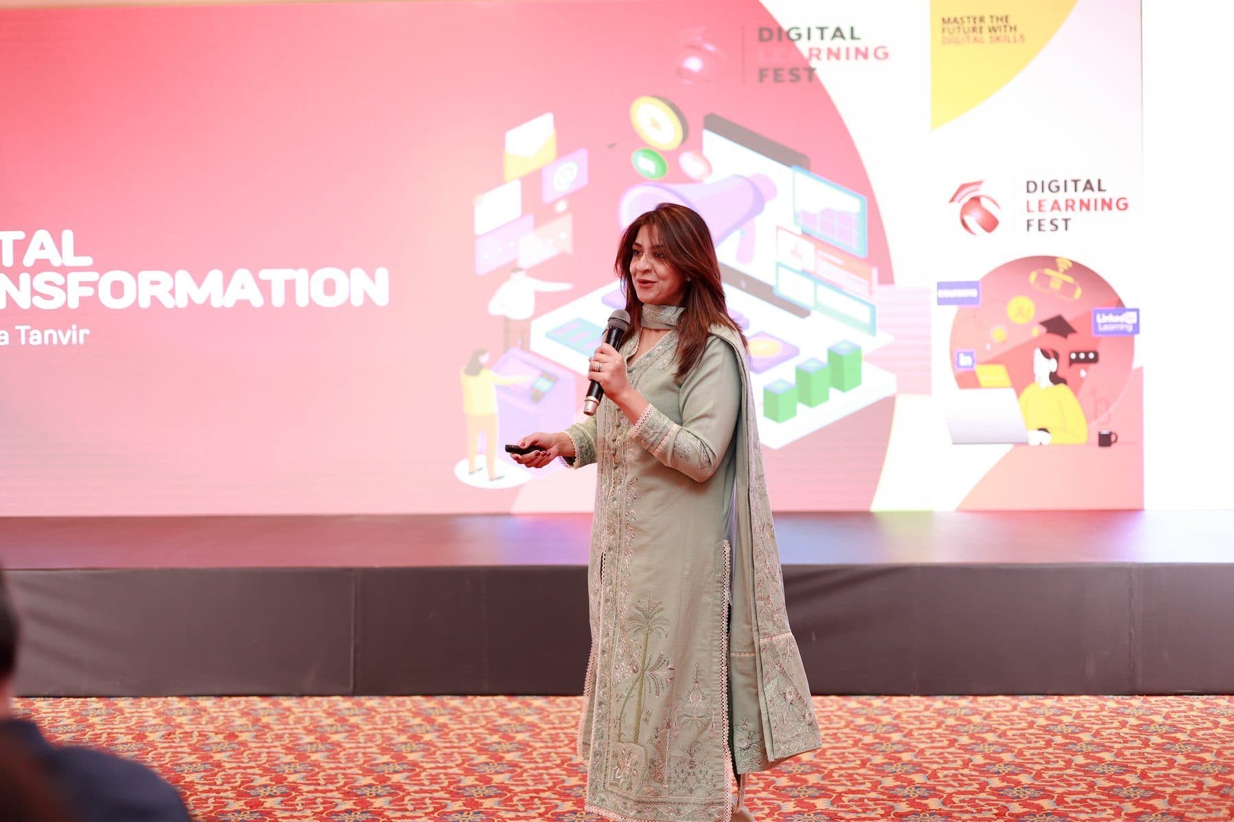 A speaker at the Digital Learning Fest in front of a full-stage digital transformation screen