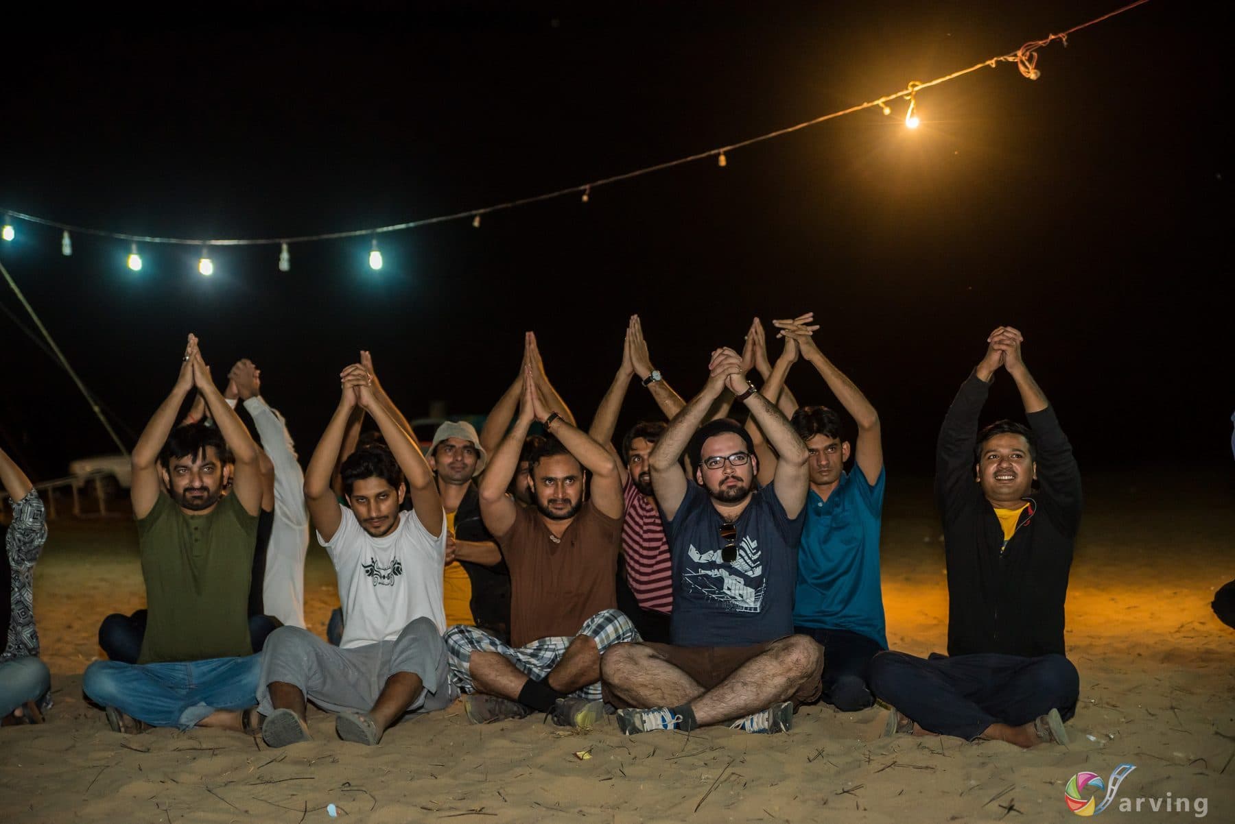 A retreat group sitting in a circle outdoors at night under strung lights