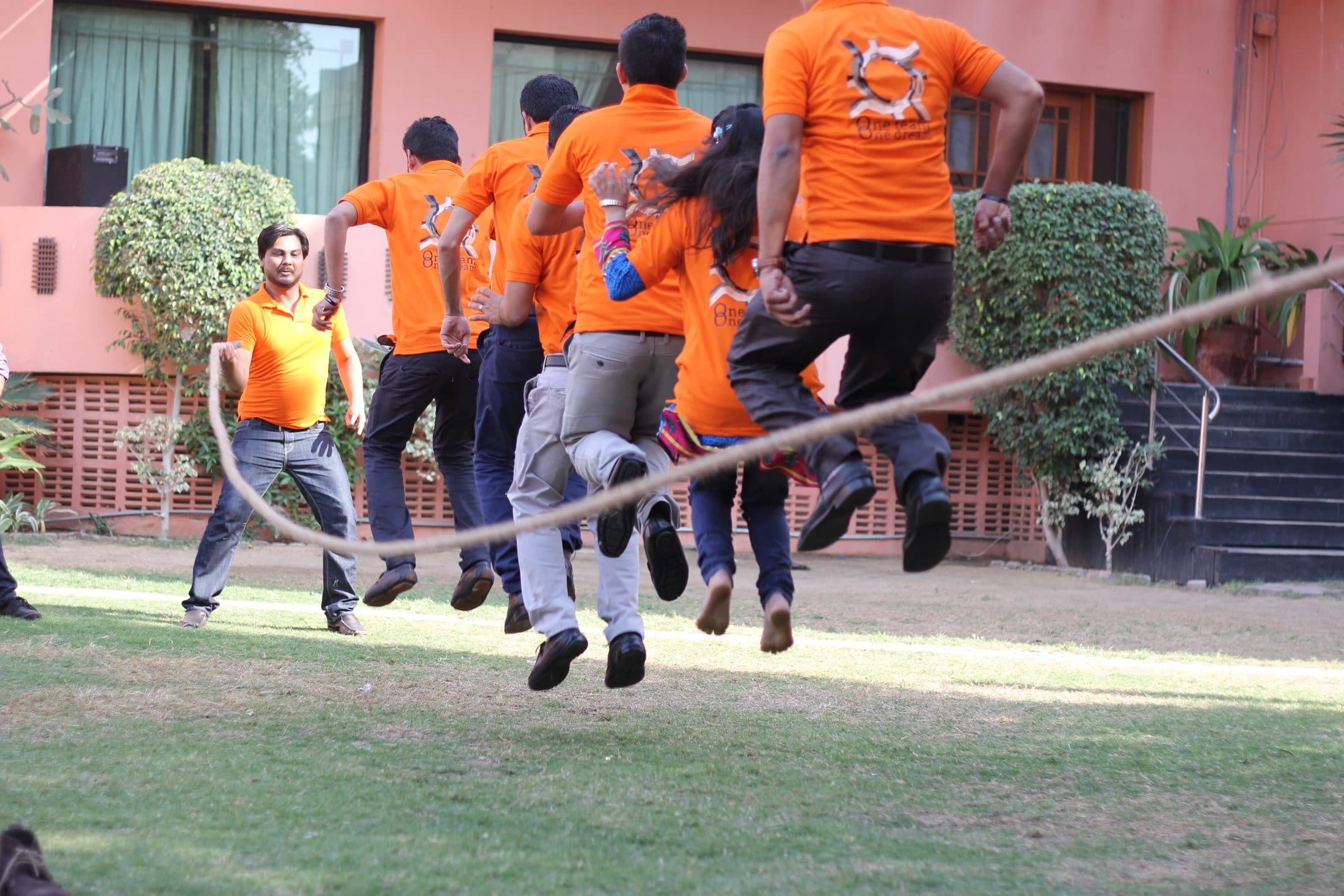 A whole team caught mid-air over a swinging rope on a lawn