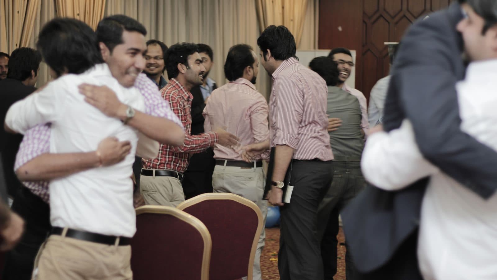 Participants standing close in pairs at the end of a session, holding on to one another