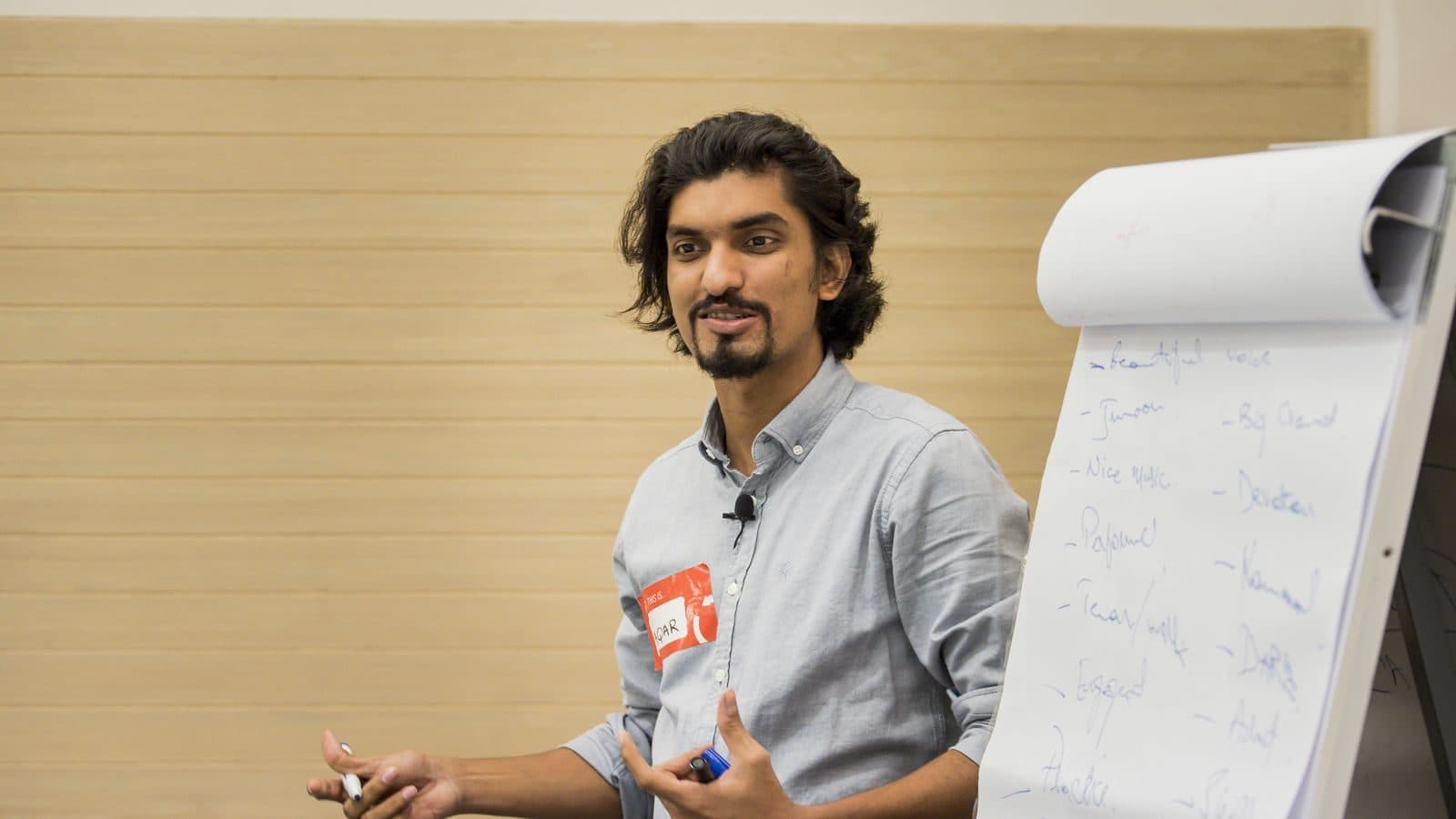 A trainer standing at a flipchart pad, talking with one hand open