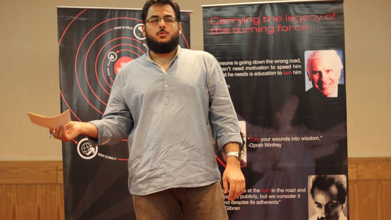 A speaker mid-sentence in front of a dark Torque banner, one hand out to the room