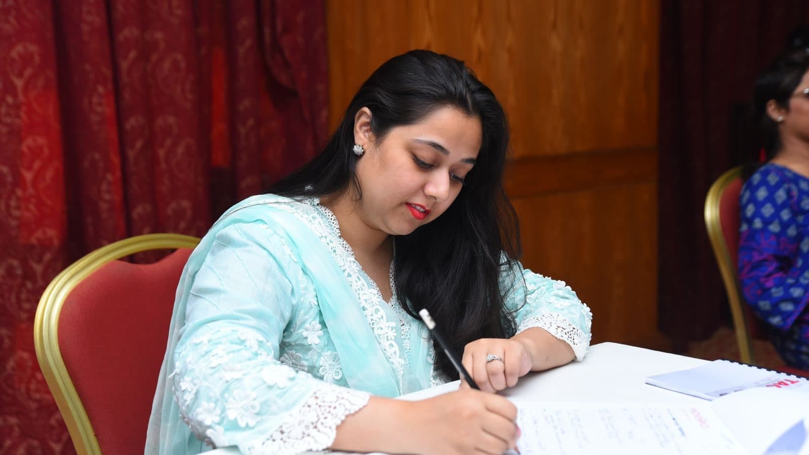 A participant writing steadily at a table, everything else out of focus